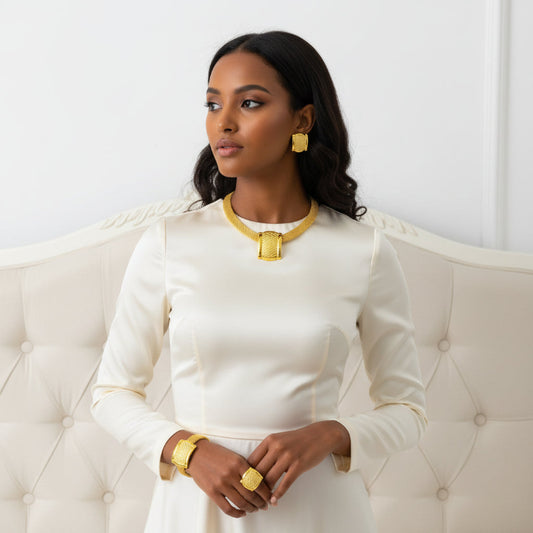 Gold jewelry set including necklace, earrings, and ring on a mannequin.