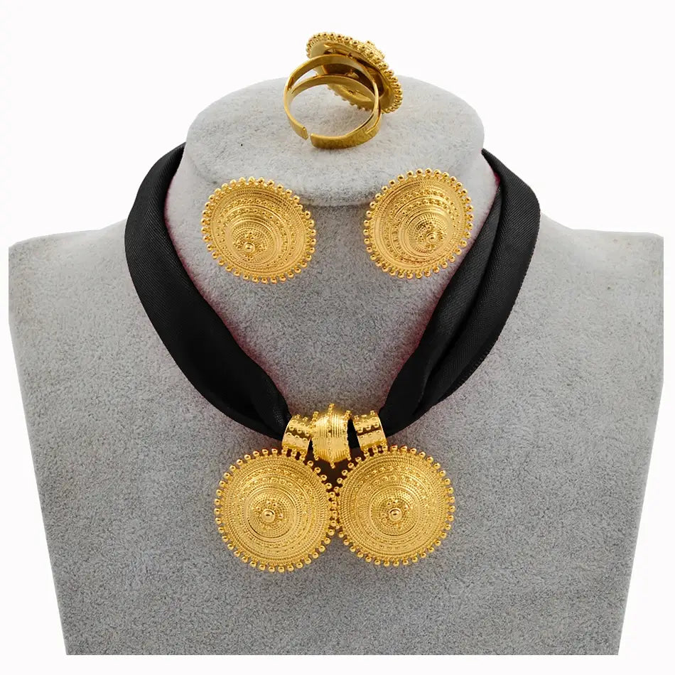 Gold necklace and earrings on a gray mannequin with a black scarf