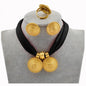 Gold necklace and earrings on a gray mannequin with a black scarf