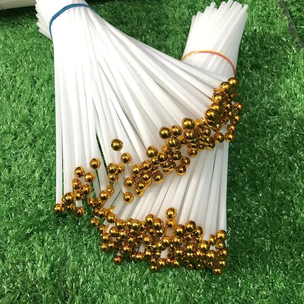 White sticks with gold balls on a green grass background