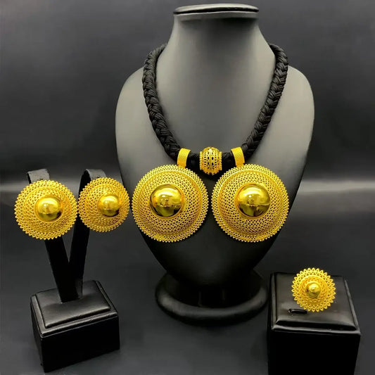 Gold necklace and earrings set on a black mannequin and stands against a dark background