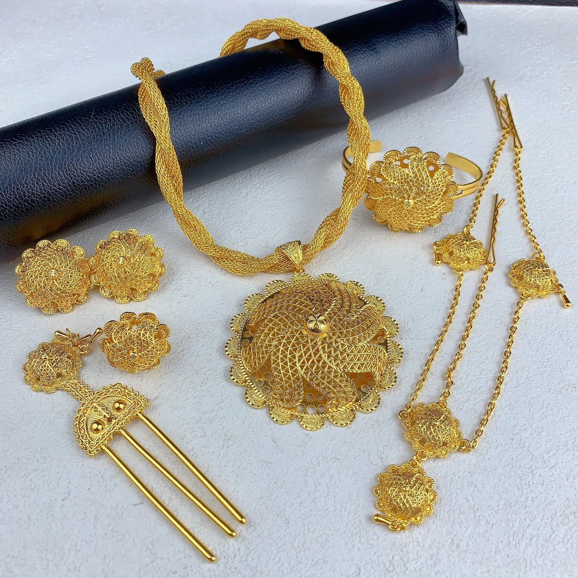 Set of gold jewelry including necklace, earrings, and ring on a white background