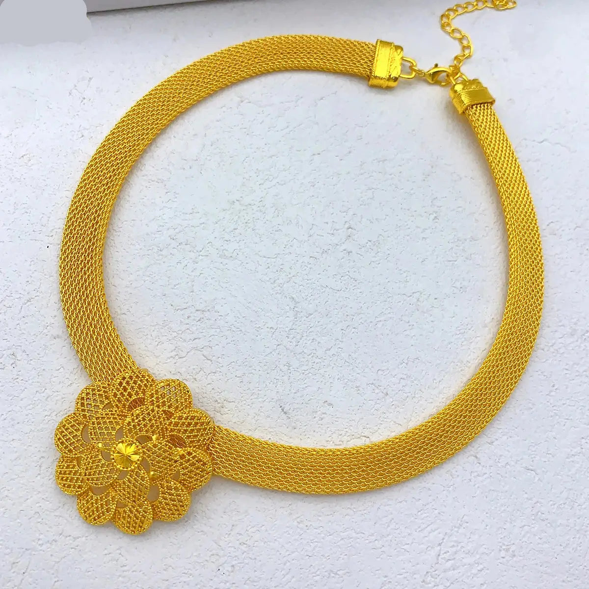 Gold necklace with a floral design on a white background