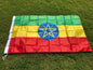 Flag with green, yellow, and red horizontal stripes and a blue circle with a yellow star on a grass background