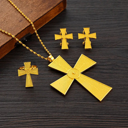 Gold jewelry set including a necklace, ring, and earrings on a dark wooden surface.