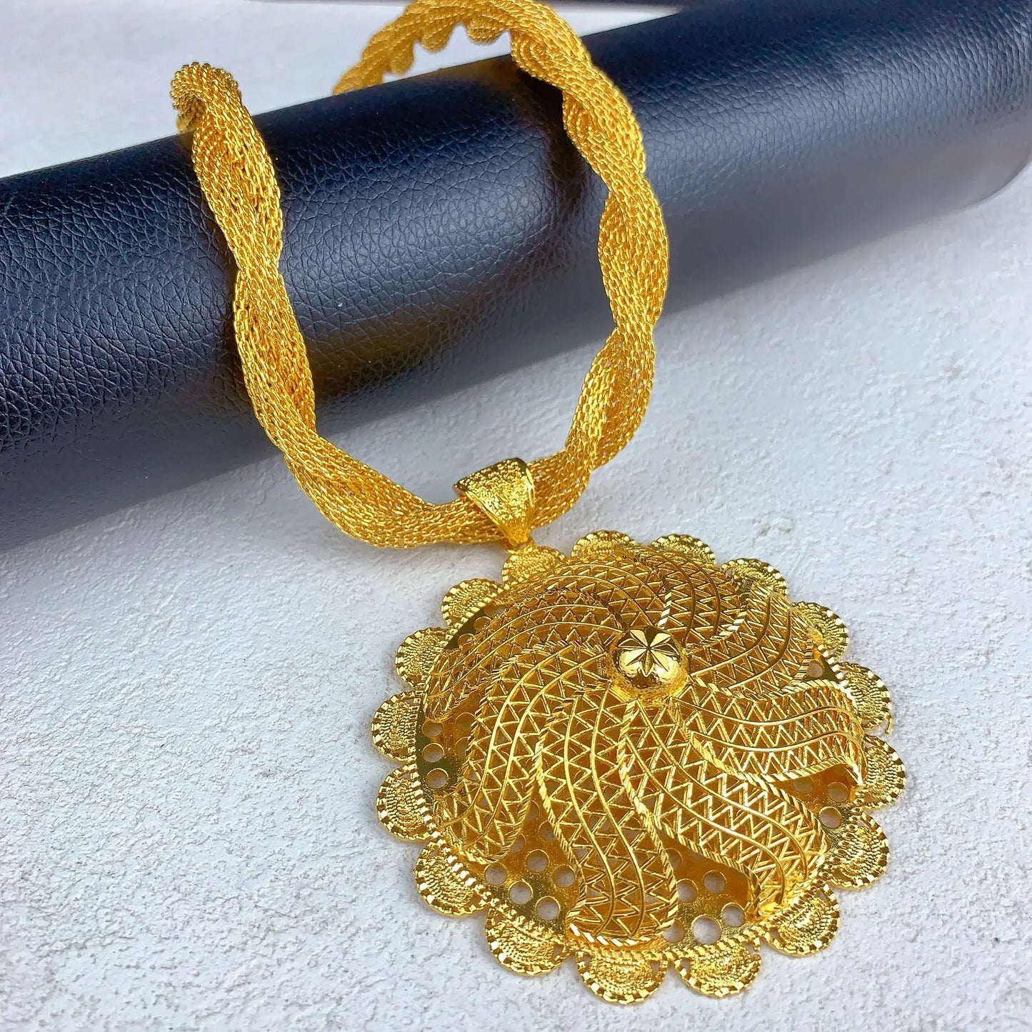 Gold necklace with intricate pendant on a textured surface