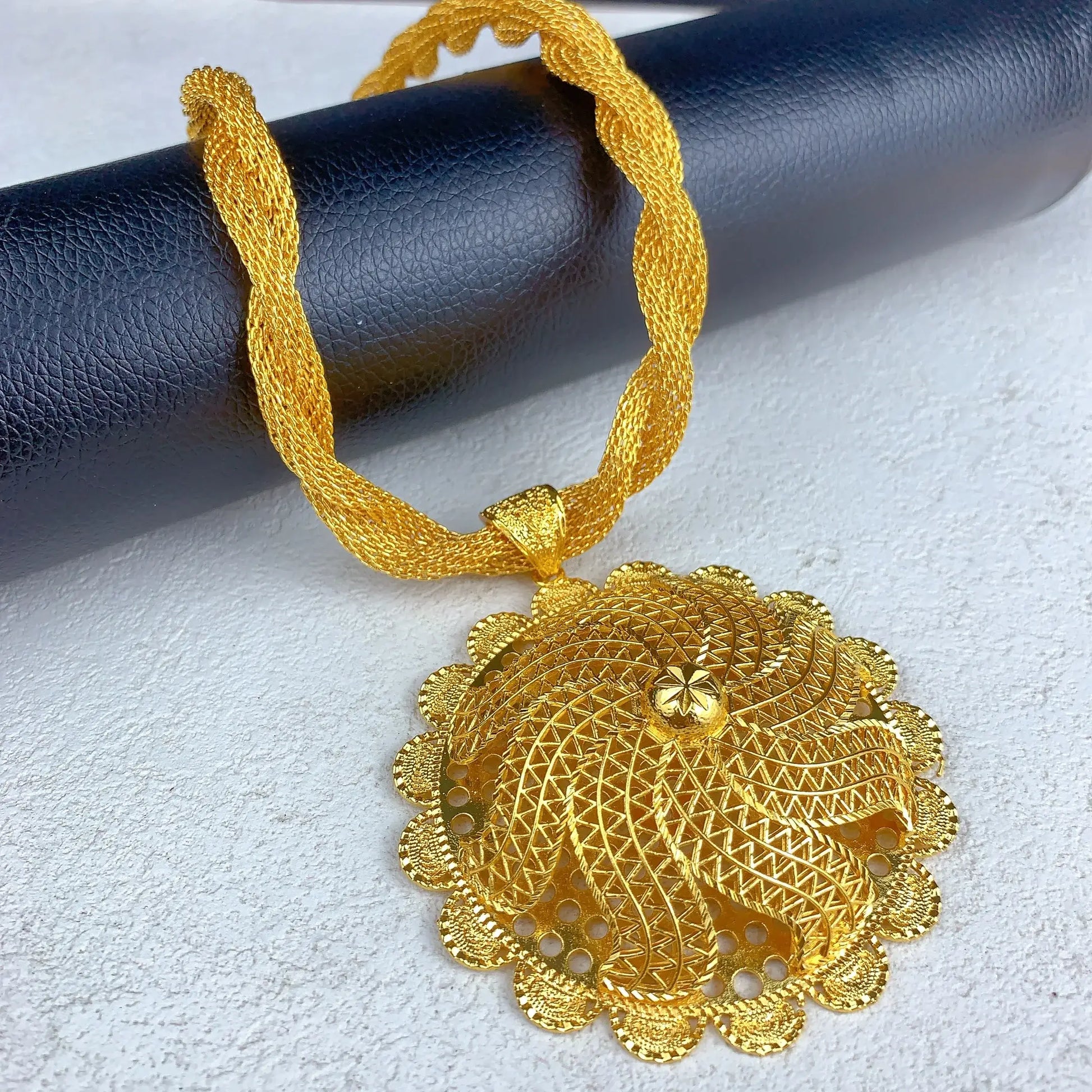 Gold necklace with intricate pendant on a textured surface