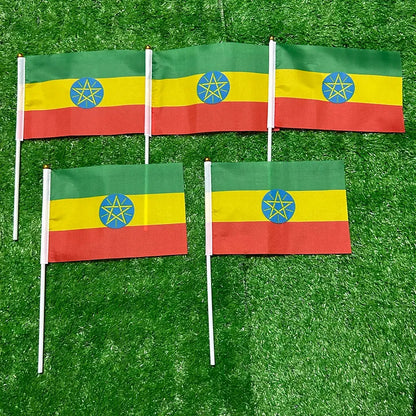 Four flags with a green, yellow, and red design on a grassy background