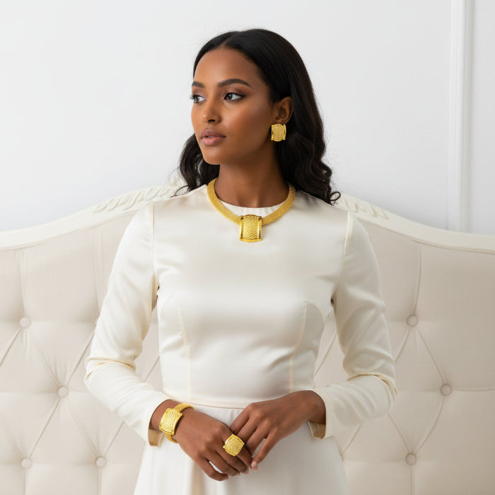 Gold jewelry set including necklace, earrings, and ring on a mannequin.