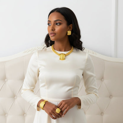 Gold jewelry set including necklace, earrings, and ring on a mannequin.