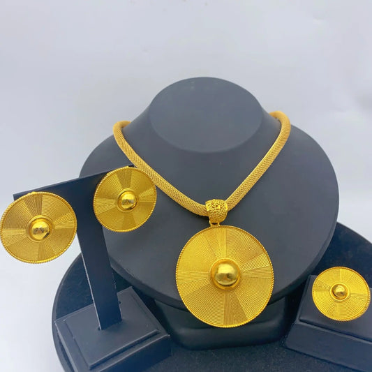 Gold necklace and earrings set on a gray stand with a white background