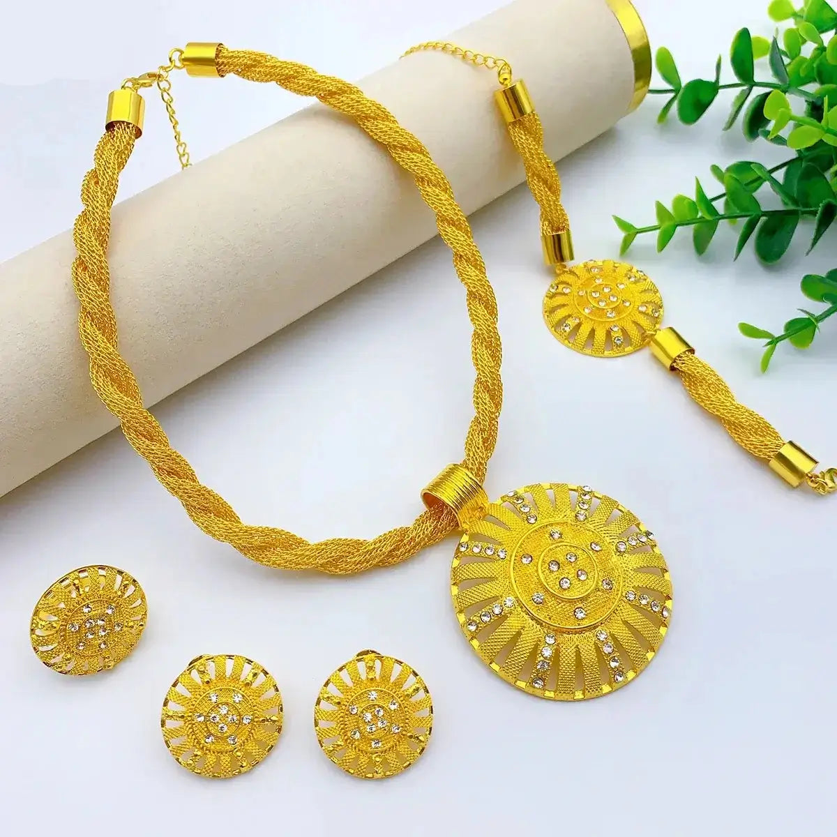 Gold jewelry set with necklace, earrings, and pendant on a white background