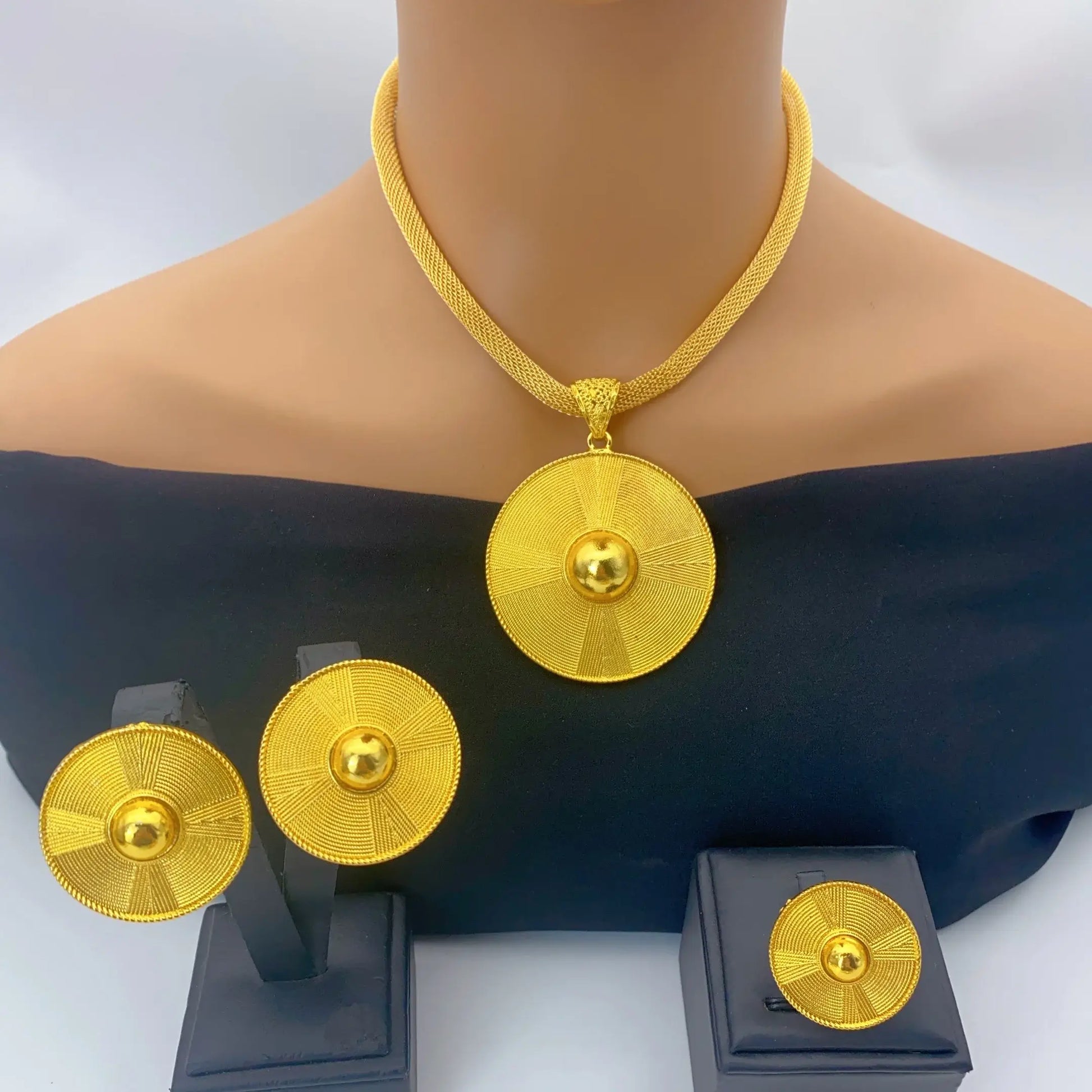 Gold necklace and earrings set on a mannequin with a white background