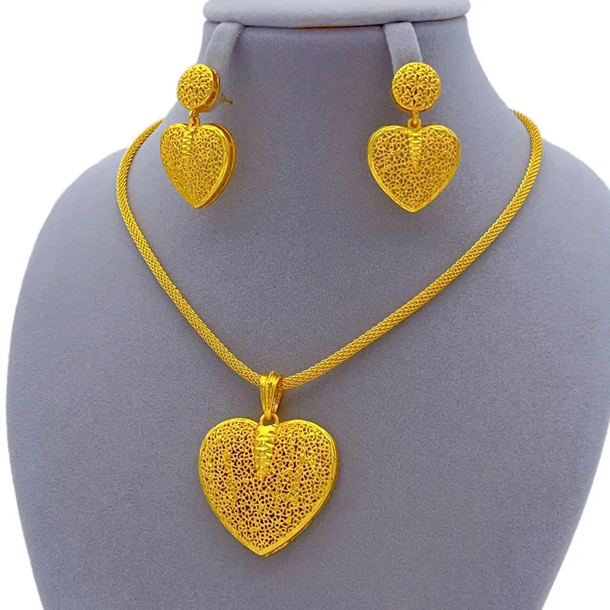 Gold heart-shaped necklace and earrings on a mannequin bust.
