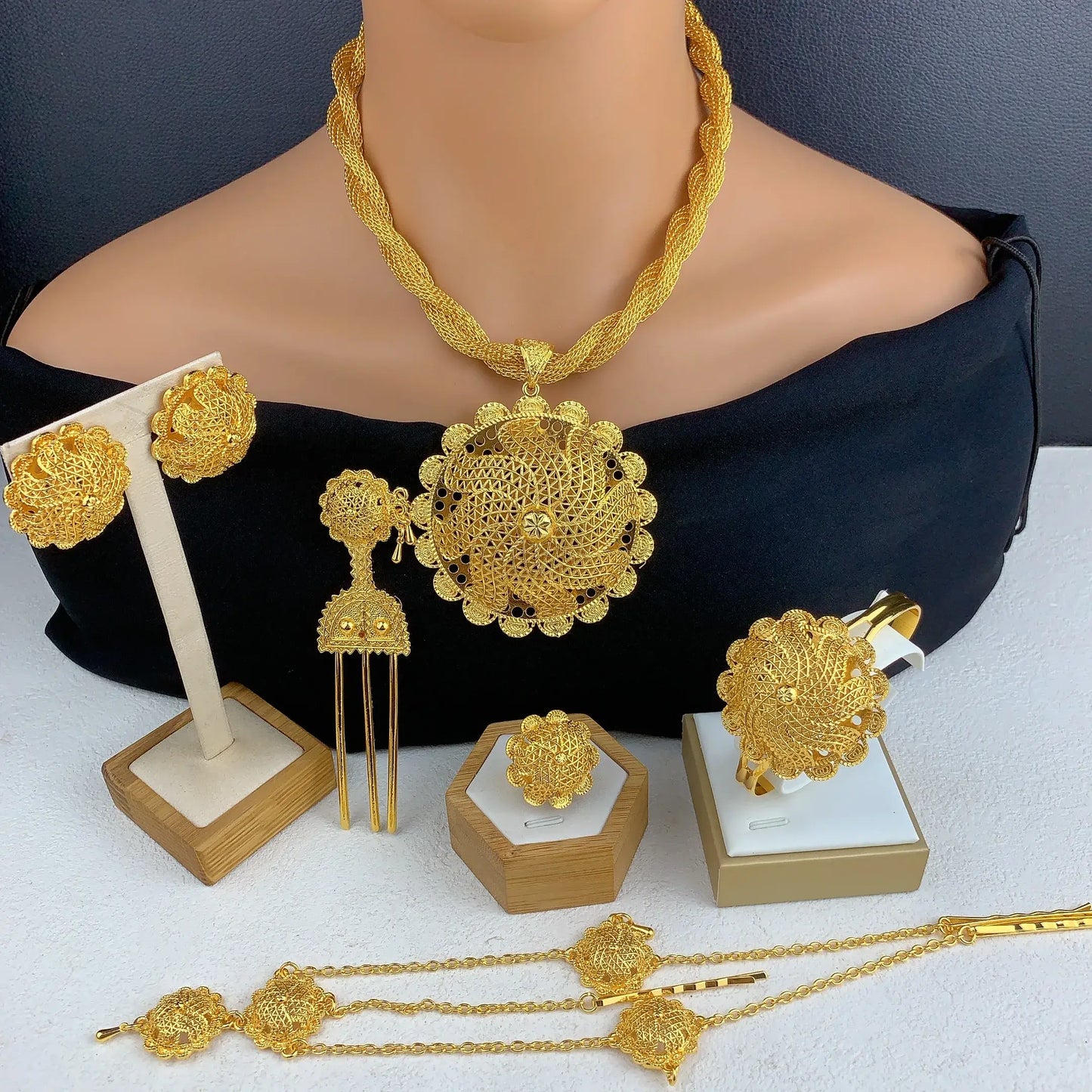 Gold jewelry set including necklace, earrings, and bangles on a mannequin and white surface.