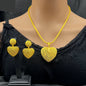 Gold heart-shaped necklace and earrings on a mannequin with a black top.