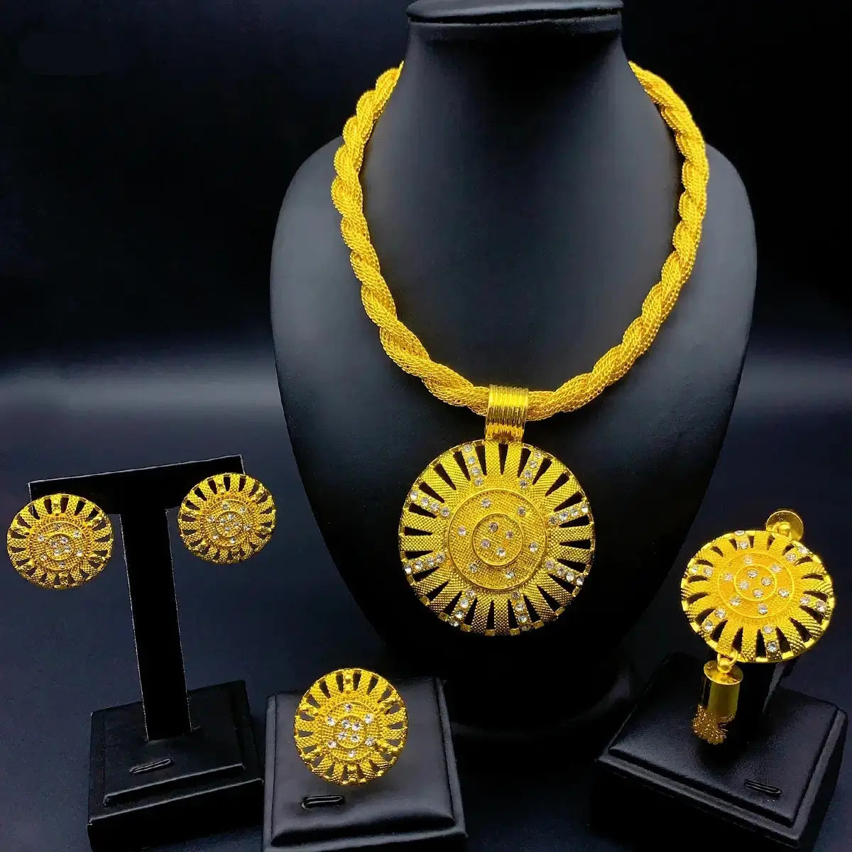 Gold necklace and earrings set on a black stand with a dark background