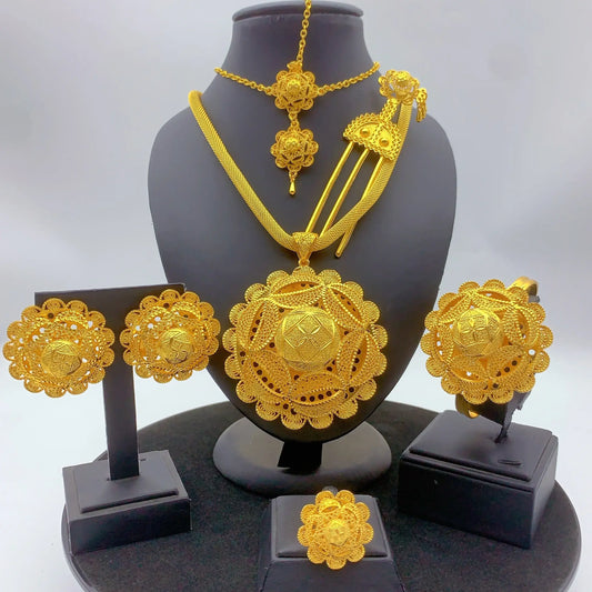 Gold jewelry set including necklace, earrings, and ring on a black stand with a white background
