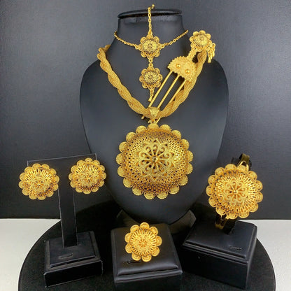 Gold jewelry set including necklace, earrings, and hairpin on a black stand against a dark background.