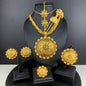 Gold jewelry set including necklace, earrings, and hairpin on a black stand against a dark background.