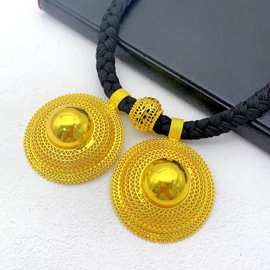 Gold necklace with black cord on a white background