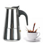 Stainless steel espresso maker with a cup of coffee being poured into it on a white background