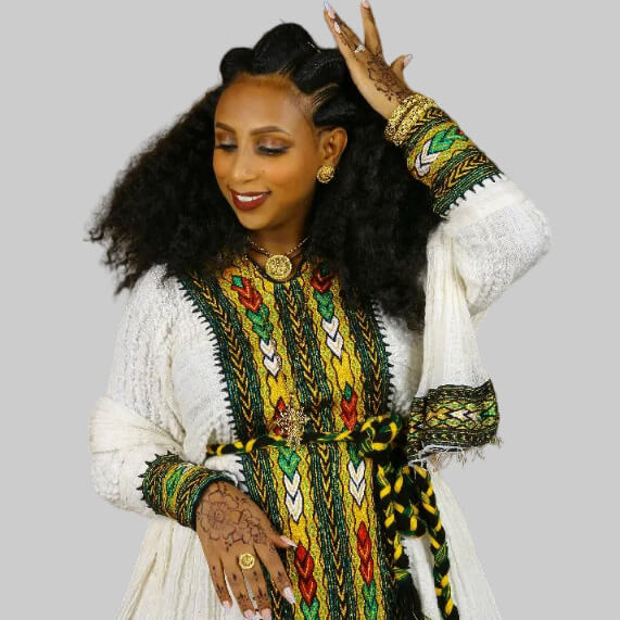 Woman wearing a colorful traditional outfit with intricate patterns on a gray background
